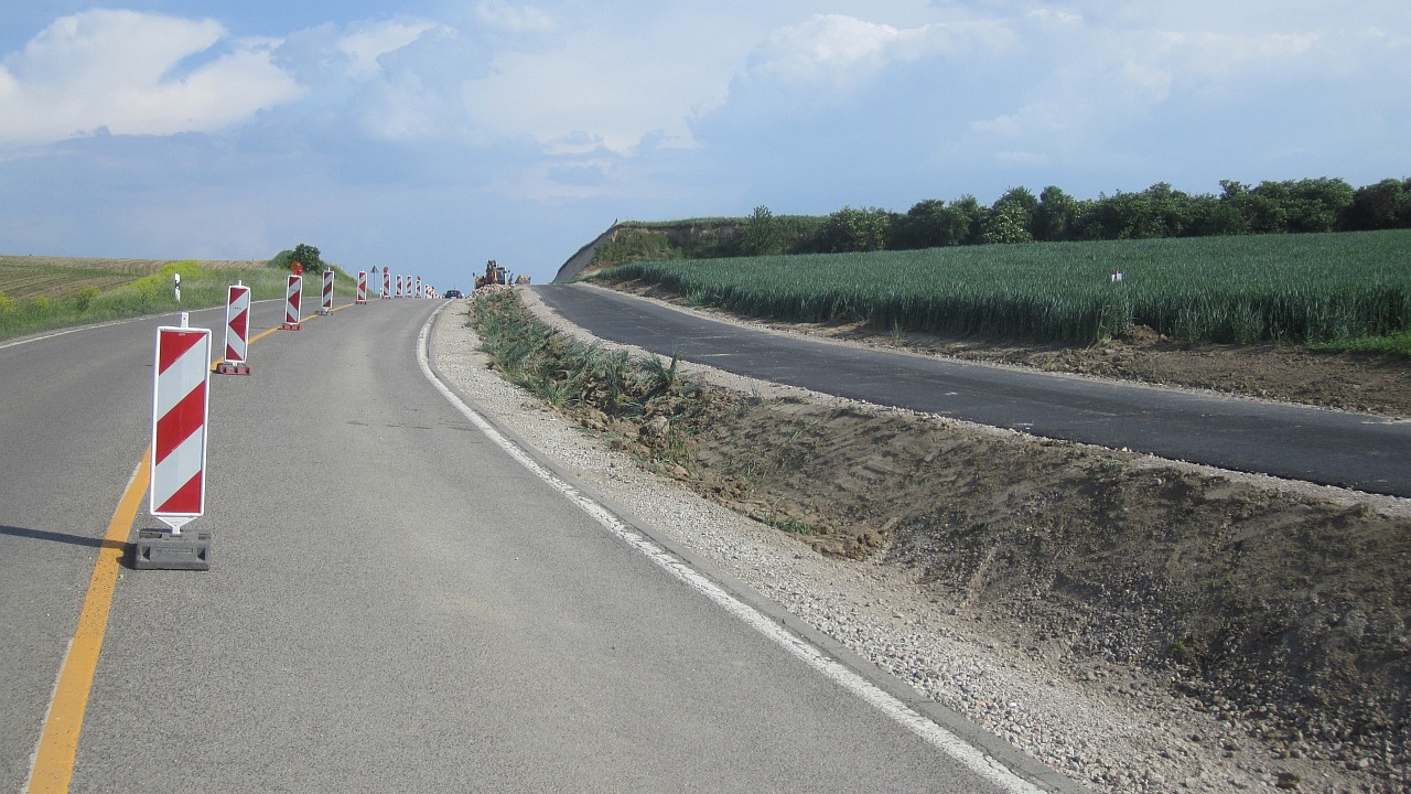 an einer Straße führen Warnbarken entlang, rechts davon befindet sich der Radweg, der zu diesem Zeitpunkt noch ausgebaut wird