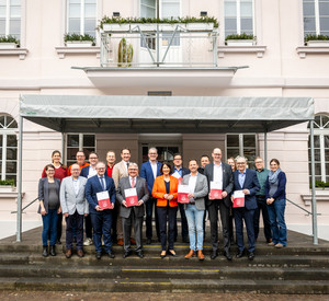 Wirtschaftsministern Daniela Schmitt hat den zehn Kommunen des kommunalen Verbundprojekts „Mitten am Rhein“ im Rathaus in Remagen zehn KIPKI-Förderbescheide in Höhe von insgesamt rund 3,8 Millionen Euro überreicht.
