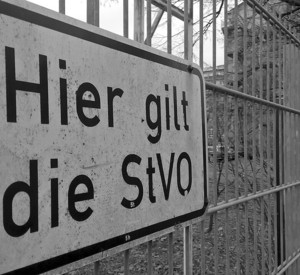 weißes Schild an einem Zaun mit der Aufschrift: "Hier gilt die StVO".
