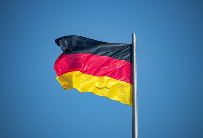Im Wind wehende Fahne von Deutschland vor blauem Hintergrund