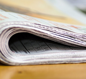 In der Mitte eingerollte Zeitung liegt auf einem Tisch.