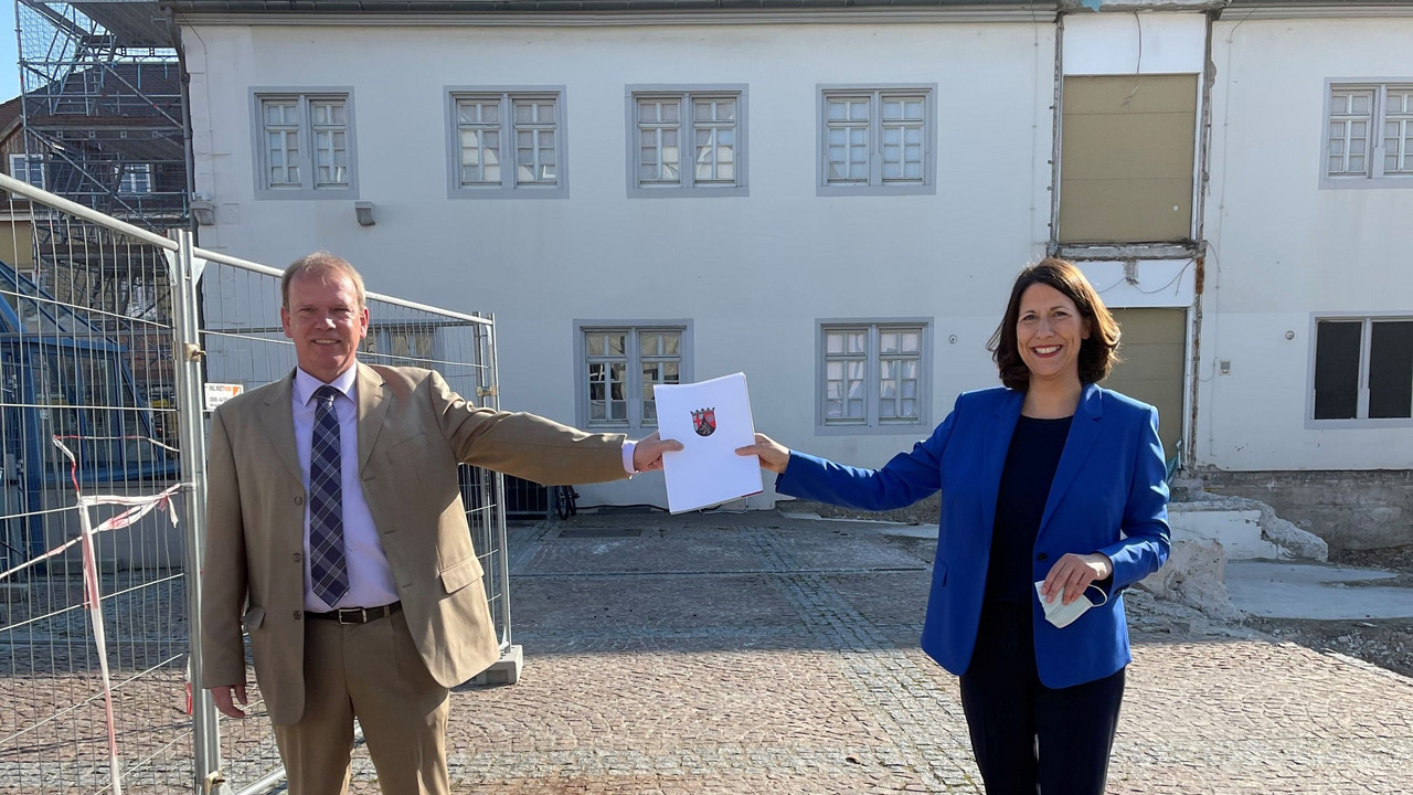 Staatssekretärin Daniela Schmitt übergibt Bürgermeister Christoph Burkhard auf dem Festplatz vor dem Museum den Förderbescheid zum barrierefreien Ausbau
