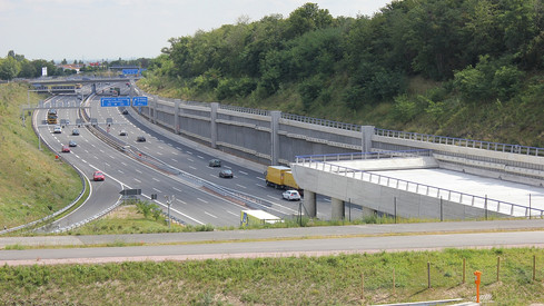 Autos und Lkw bewegen sich aus dem Hechtsheimer Tunnel hinaus und in den Tunnel hinein, zwei Fahrzeuge verlassen die Autobahn über die Anschlussstelle